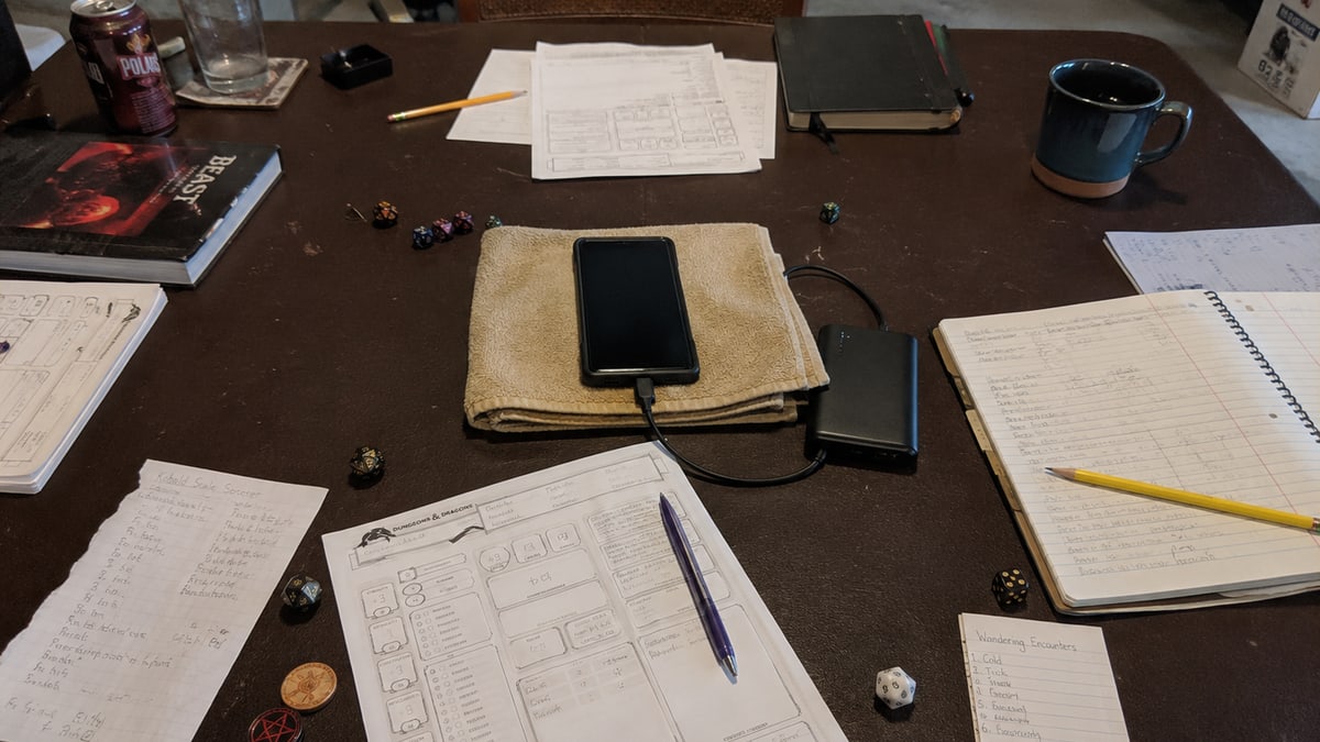 A phone placed at the center of a tabletop role-playing table among character sheets and notebooks