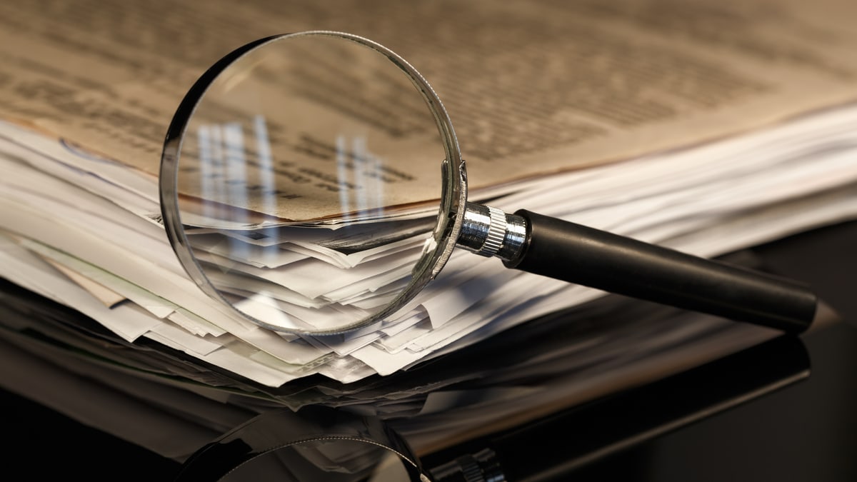 A magnifying glass resting on a notebook filled with notes